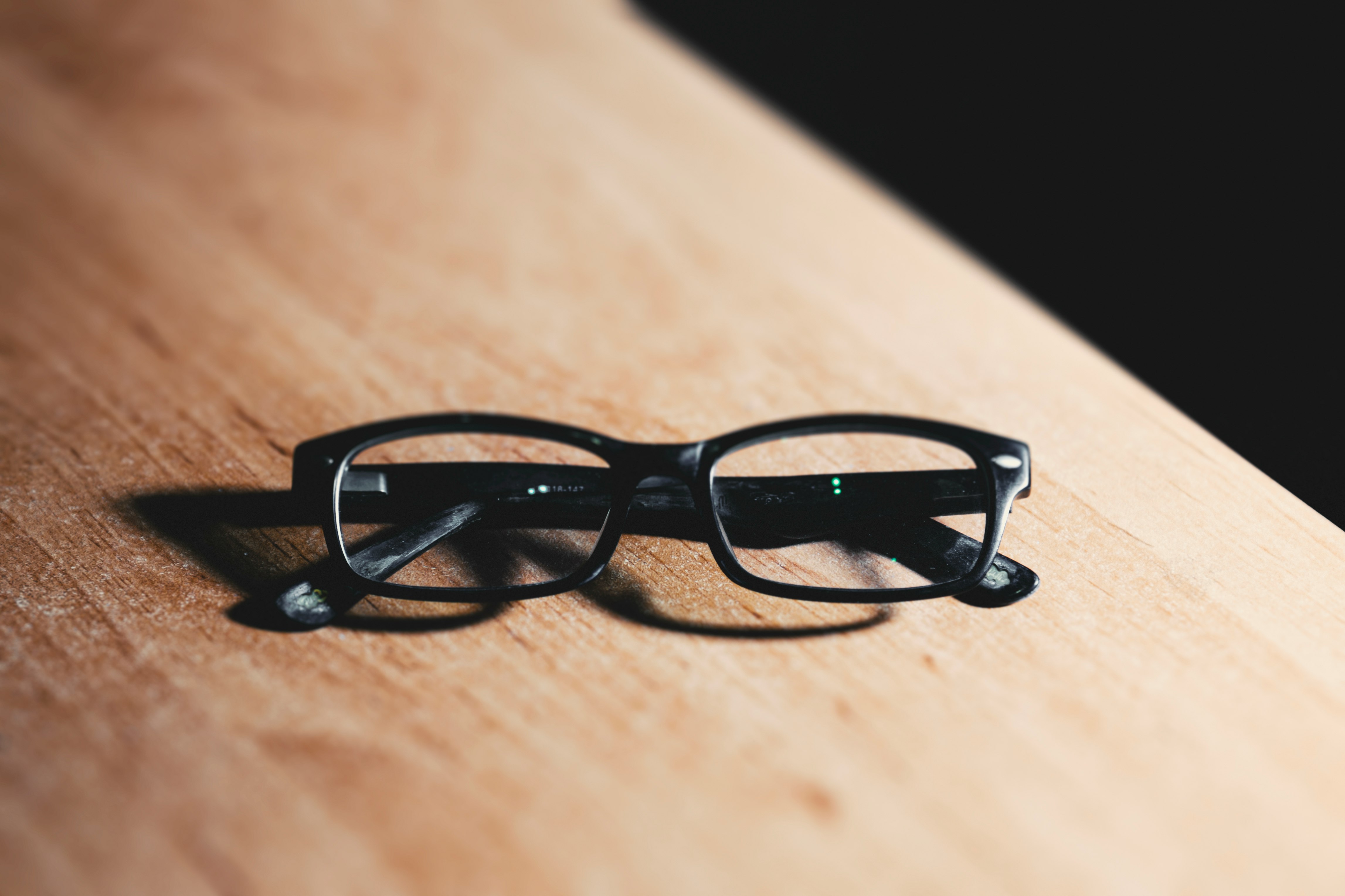 black framed eyeglasses on brown wooden table